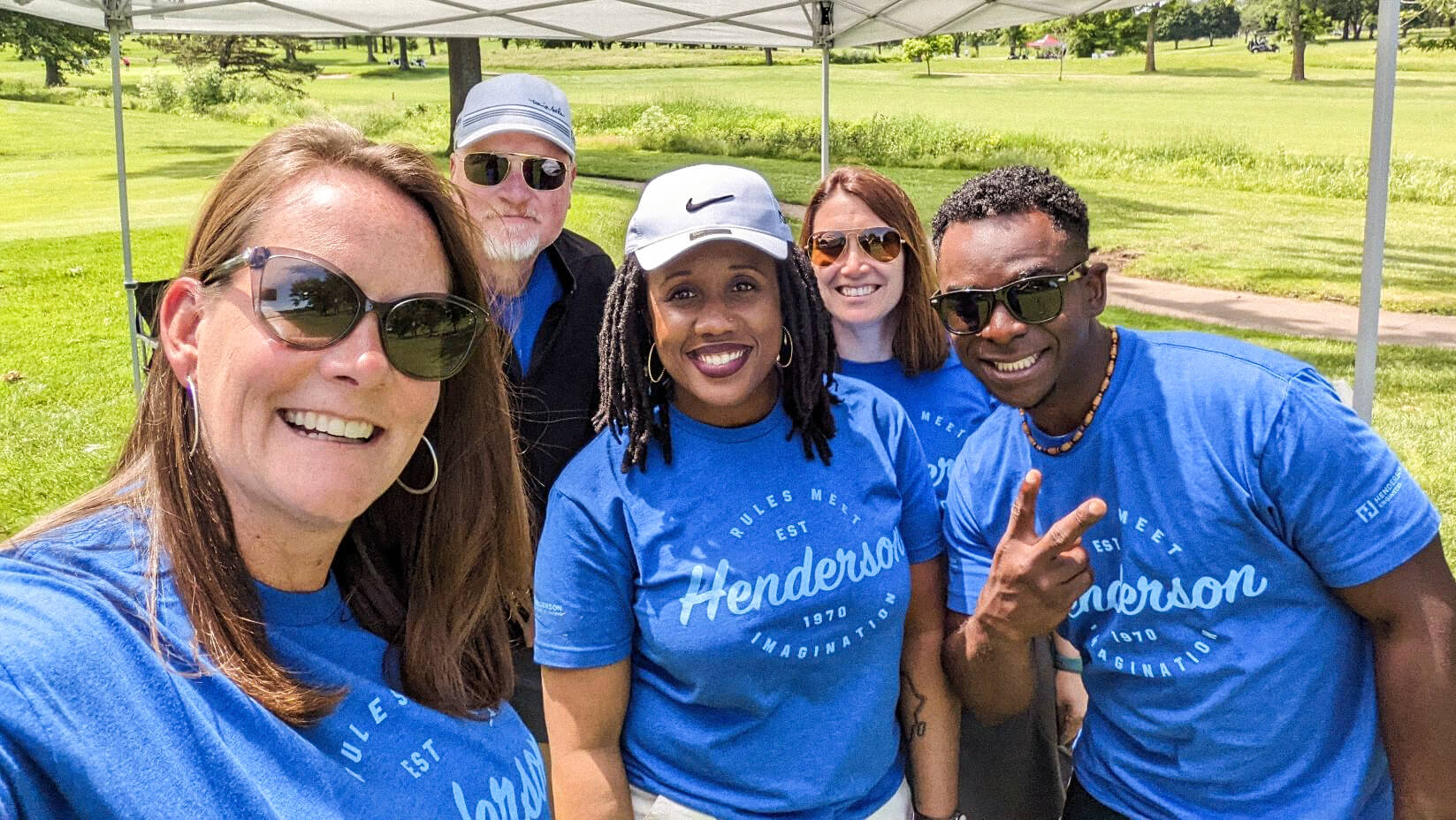 Five Henderson Engineers employees smiling at the client golfing event.