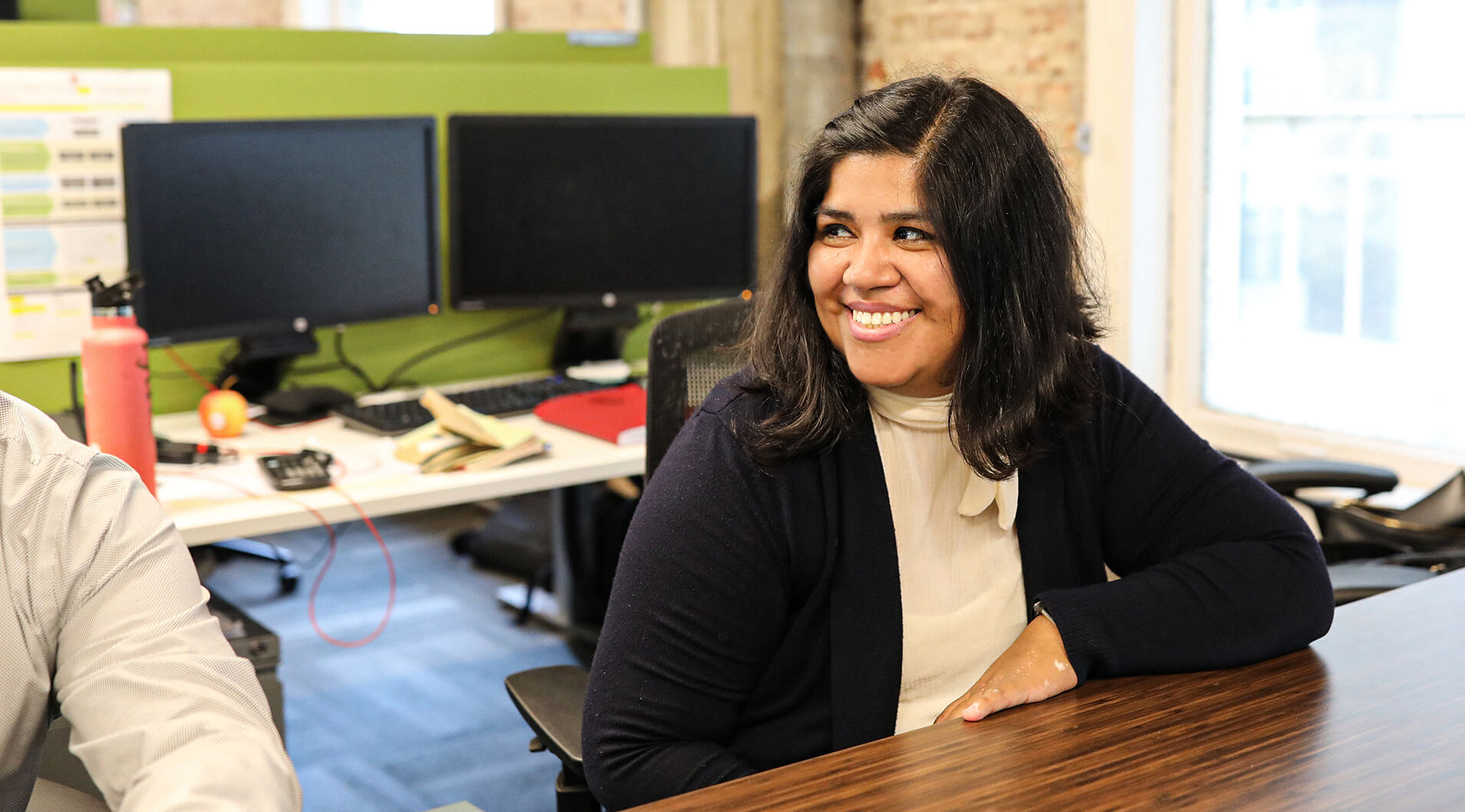 A Henderson employee smiling at co-workers at a conference table.