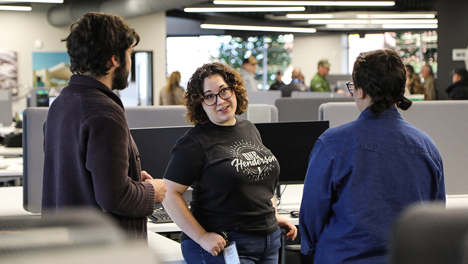 Three Henderson Engineers employees chatting together in the office.