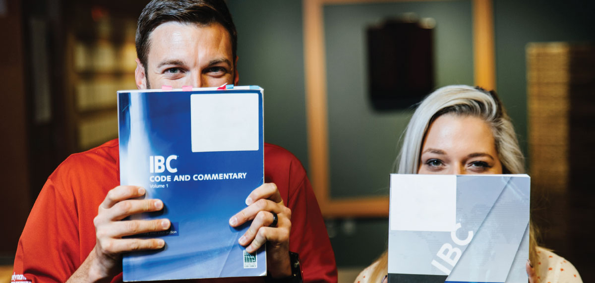Two engineers peering over the IBC Code and Commentary books at the camera.