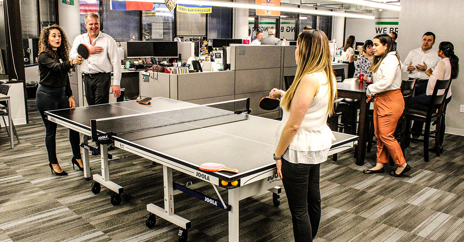 Two female employees playing ping pong in the Houston office at a client event.