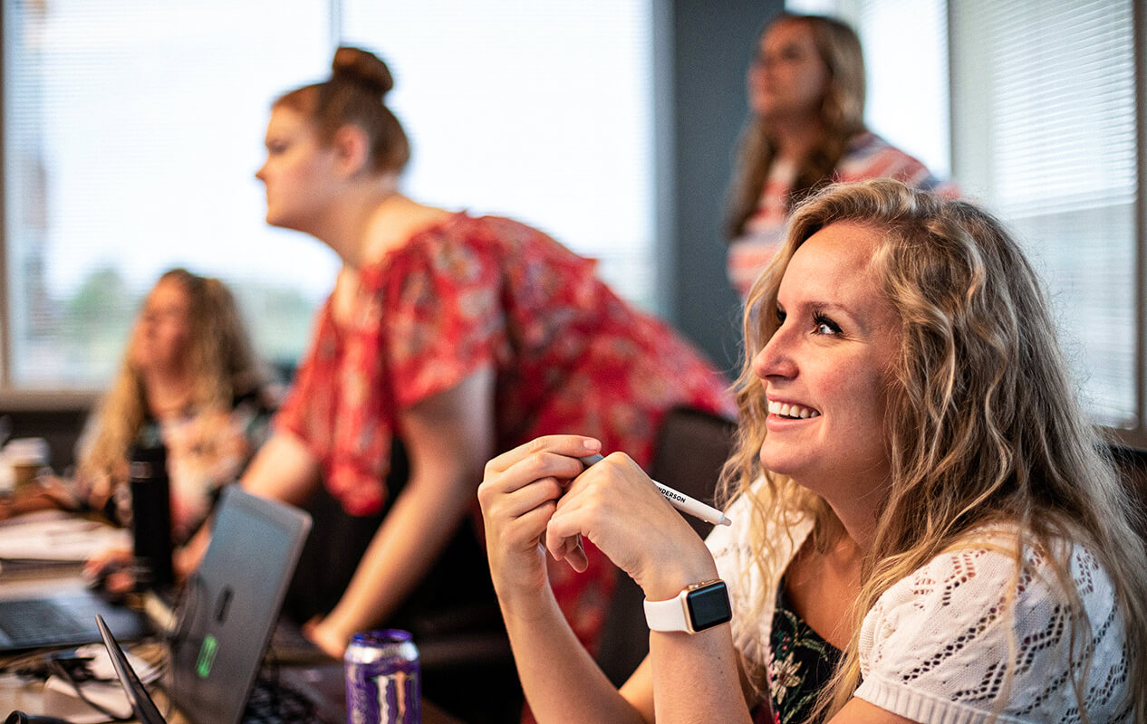 A female Henderson Engineers employee smiling in a meeting while looking at the presentation.