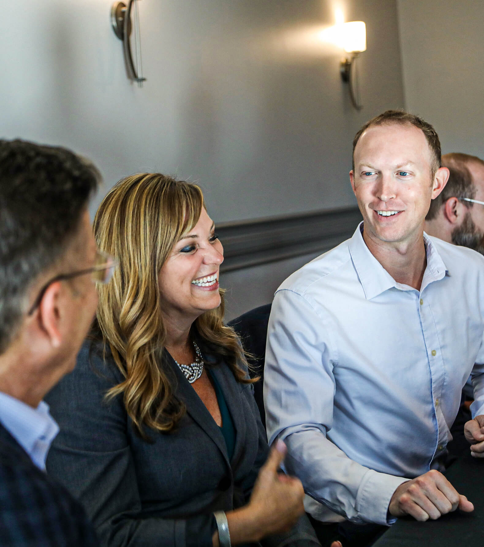 Three members of the Henderson Engineers leadership team chatting at a conference room table.